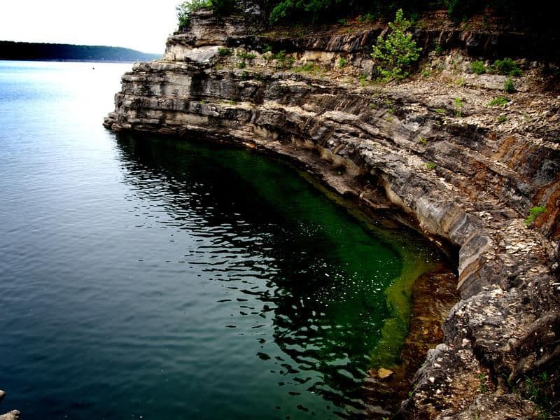 Beautiful rock formation extending into the clear water Photos