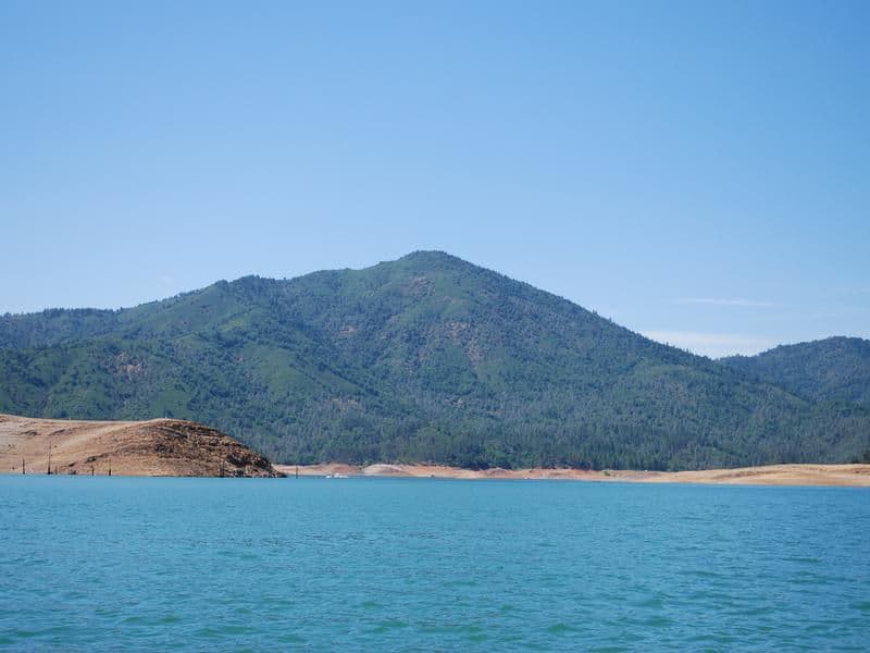 A stunning view of vast blue waters sit below lush green mountains Photos